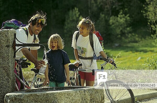 Paar mit Mädchen und Fahrräder am Brunnen