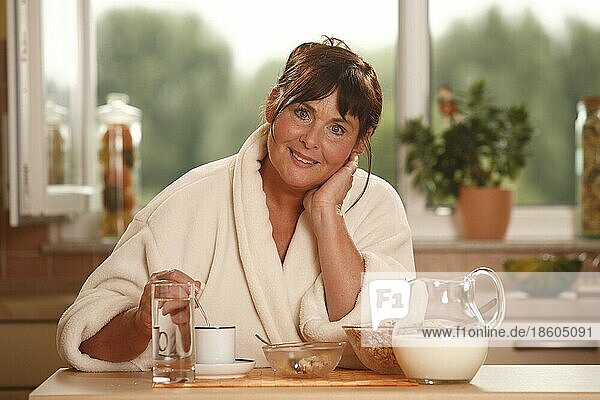 Frau beim Frühstück  Frühstück  frühstücken  Kanne Milch  Schüsseln  Müsli  Tasse Kaffee  Glas Wasser  frühstückt