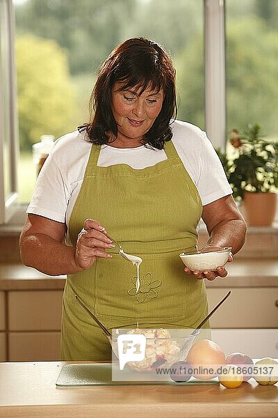 Frau bereitet Obstsalat mit Joghurt zu  zubereiten  Schüssel  Salatbesteck  Löffel