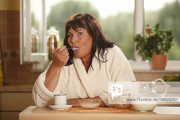 Frau beim Frühstück  Frühstück  frühstücken  Kanne Milch  Schüsseln  Müsli  Tasse Kaffee  frühstückt  Löffel