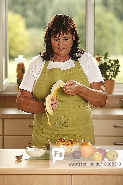 Frau bereitet Obstsalat zu  schält Banane  zubereiten  Schüssel  schält  schälen  Joghurt