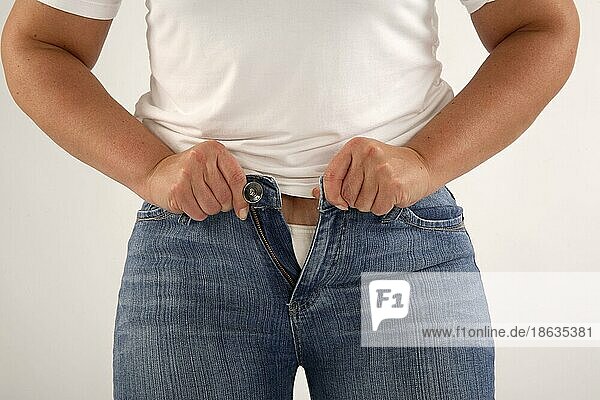 Frau versucht Jeans zuzuknoepfen  zu eng  zu klein  zu enge Hose