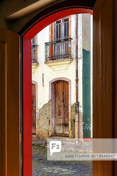 Alte Tür in kolonialer Architektur  die sich im Laufe der Zeit verschlechtert hat  gesehen durch eine andere Tür  die ebenfalls alt ist und die gleiche Architektur aufweist  in der Stadt Ouro Preto  Ouro Preto  Minas Gerais  Brasilien  Südamerika