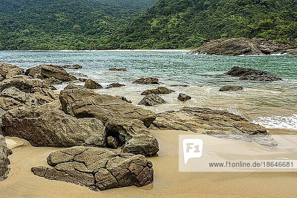 Felsiger und verlassener Strand  umgeben von dichtem und erhaltenem Regenwald mit ruhigem Wasser und lebhaften Farben in Trindade  Paraty  Rio de Janeiro  Brasilien  Südamerika