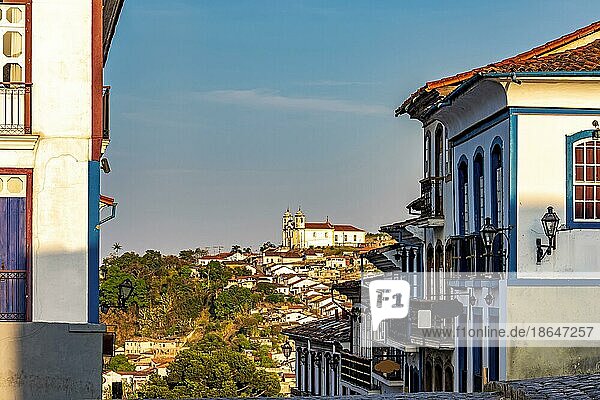 Straßen und Häuser in der historischen Stadt Ouro Preto in Minas Gerais mit einer Kirche auf einem Hügel im Hintergrund  Brasilien  Südamerika