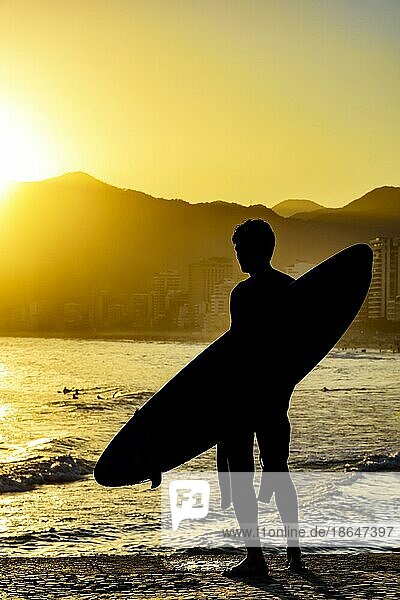 Surfer Silhouette mit seinem Longboard mit Blick auf die Iapnema Strand Wellen in Rio de Janeiro während des Sonnenuntergangs  Brasilien  Südamerika