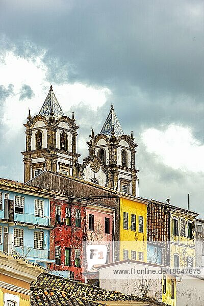 Historischer barocker Kirchturm hinter den Fassaden alter Häuser im Kolonialstil in Pelourinho in der Stadt Salvador  Bahia  Brasilien  Südamerika