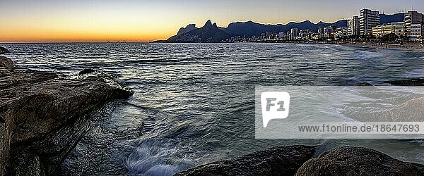 Panoramabild des Sonnenuntergangs am Strand von Ipanema in Rio de Janeiro mit dem Meer  Gebäuden und Bergen  die für die Stadt charakteristisch sind  Brasilien  Südamerika