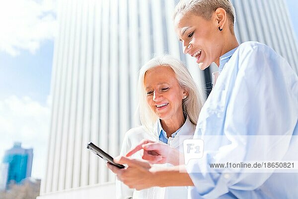 Frauen in Führungspositionen und Geschäftsfrauen in einem Geschäftsviertel  selbstbewusste Frauen lächelnd mit Blick auf ein Tablet