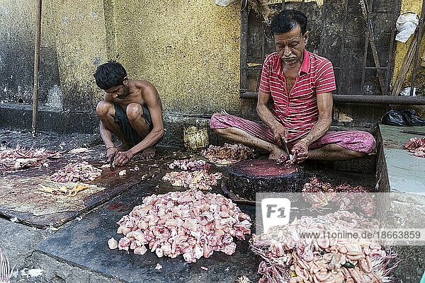 Crawford Market  today's name Mahatma Jyotiba Phule Market  wholesale market for meat  a man cuts poultry into parts  heads and chicken feet are also used  Mumbai  Maharashtra  India  Asia