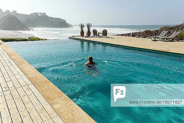 Frau schwimmt im Infinity Pool am Atlantischen Ozean  Hotel auberge Dar Najmat  Mirleft  Marokko  Nordafrika  Afrika