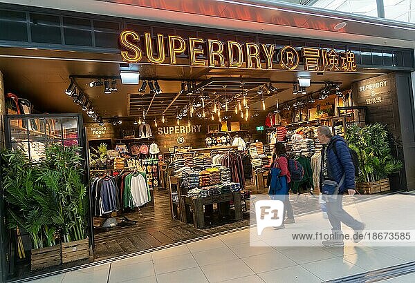 Passengers walking past Superdry clothing fashion shop  Stansted airport  Essex  England  UK