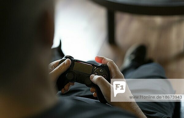 Close-up of an adult man's hands holding a joystick while playing a video game on a console. Copy space