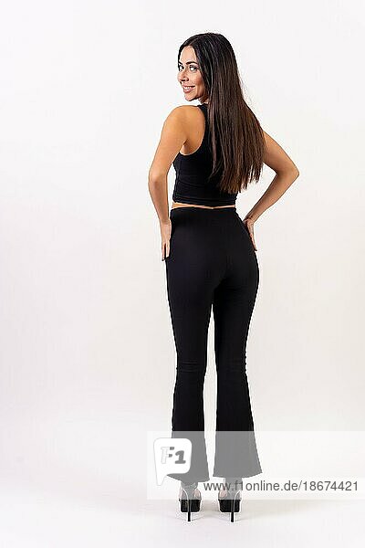 Person brunette woman in casting photos on a white background. Posed from behind dressed in black