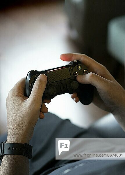 Hoher Blickwinkel auf die Hände eines erwachsenen Mannes  der einen Joystick hält  während er ein Videospiel auf einer Konsole spielt