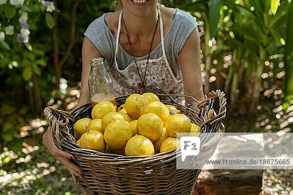 Eine Frau trägt einen Weidenkorb voller frischer Zitronen