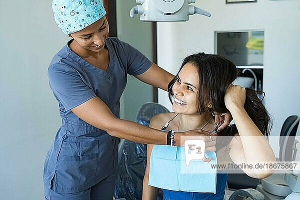 Schöne junge Frau in Zahnarztpraxis lächelnd und Blick auf ihre Kieferorthopäden. Konzept der Zahnaufhellung  Zahnpflege  Mundgesundheit  Zahnmedizin Werbung
