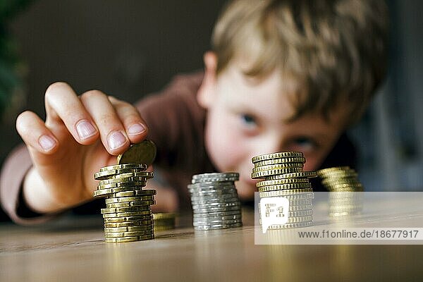 Symbolfoto zum Thema Sparen in der Kindheit. Ein fünfjähriger Junge stapelt Kleingeld auf einem Tisch. Berlin  19.05.2023  Berlin  Deutschland  Europa