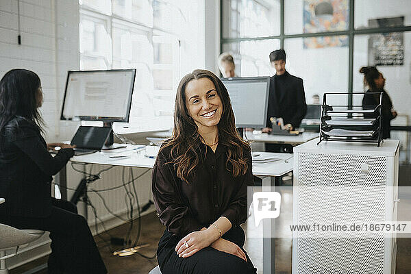 Porträt einer lächelnden Geschäftsfrau  die im Büro eines Unternehmens sitzt