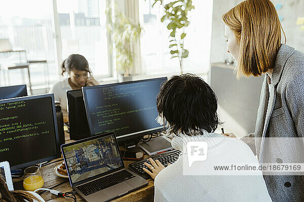 Manager diskutiert mit Programmierer über Computer am Schreibtisch im Büro