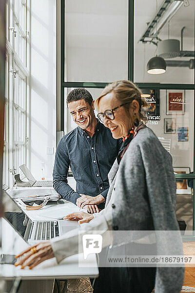 Happy male and female business people at desk in modern office
