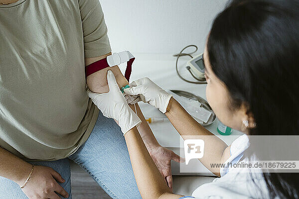 Hohe Winkel Ansicht der Arzt Piercing Nadel in den Arm des Patienten für die medizinische Untersuchung in der Klinik