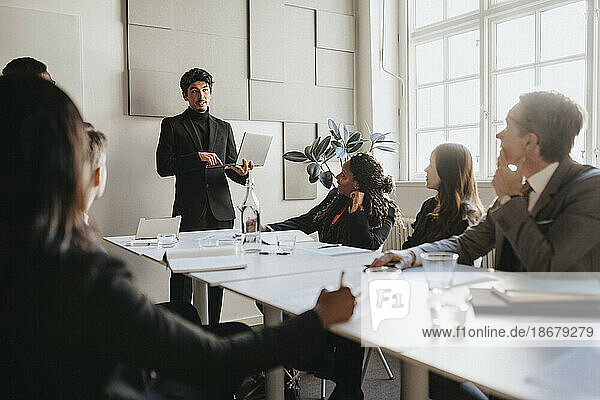 Männlicher Unternehmer  der eine Geschäftsbesprechung mit seinem Team im Sitzungssaal seines Büros abhält