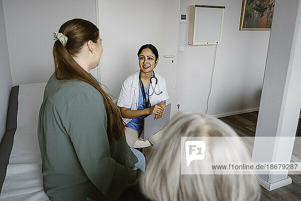 Smiling doctor discussing with patient sitting in consulting room
