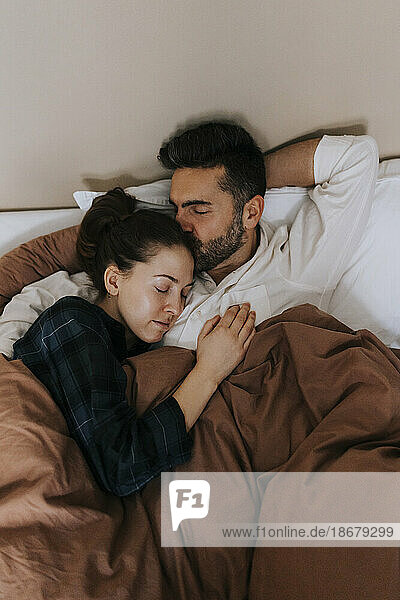 Hohe Winkel Ansicht des Mannes küssen nicht-binäre Person im Bett zu Hause entspannen