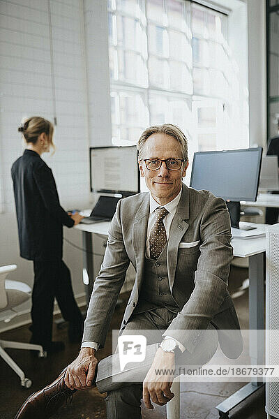 Porträt eines lächelnden Geschäftsmannes mit Brille  der im Büro sitzt