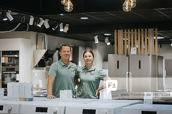 Portrait of confident male and female retail clerks standing in electronics store