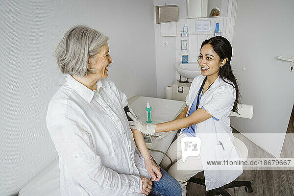 Lächelnde Mitarbeiterin des Gesundheitswesens berät ältere Patienten im Untersuchungsraum einer Klinik
