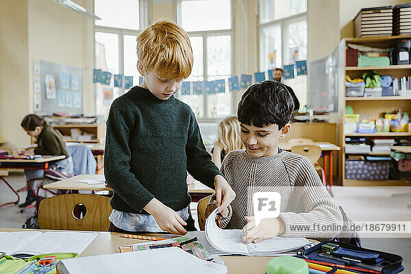 Jungen teilen ein Buch beim Lernen im Klassenzimmer