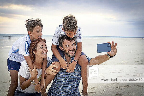 Happy family with two boys snapping a selfie with smartphone on a beach  Zanzibar  Tanzania  East Africa  Africa