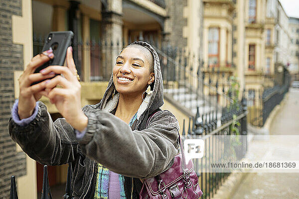 Hipster young woman taking selfie in street