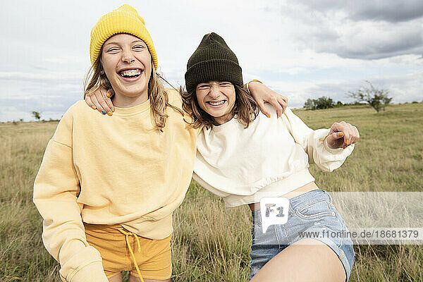 Smiling girl friends (10-11) frolicking in field