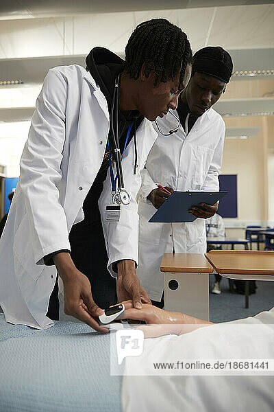 Medical students using pulse oximeter on dummy