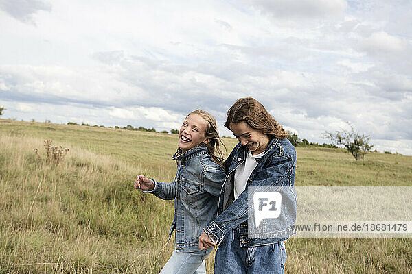 Smiling girl friends (10-11) frolicking in field