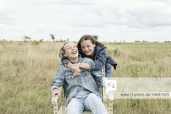 Smiling girl friends (10-11) embracing in field