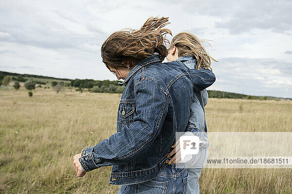 Girl friends (10-11) frolicking in field