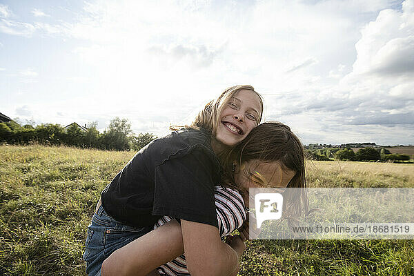 Smiling girl (10-11) giving friend piggyback ride