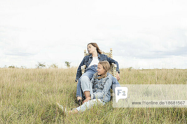 Girl friends (10-11) sitting in grassy field
