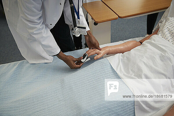 Medical student using pulse oximeter on dummy