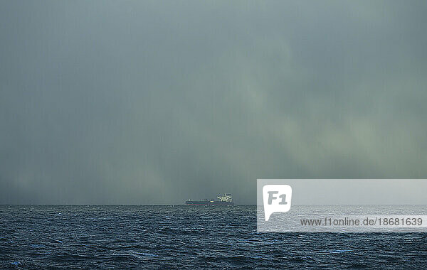 Storm clouds over industrial ship on sea