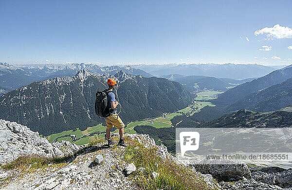 Mountaineer at the summit of the Obere Wettersteinspitze  view into the Leutasch valley  in the background summit of the Arnspitze  Wetterstein Mountains  Bavarian Alps  Bavaria  Germany  Europe