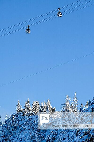 Zwei Gondeln befördert die Menschen auf den Berg. Unteres Drittel: schneebedeckte Nadelbäume auf einem Berghang. es ist strahlendd blauer Himmel  Bergbahn  gondel  Bayern  lenggries  winter  ski Oberes Drittel