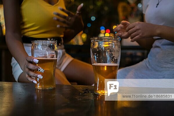 Two friends drinking beer. Detail shot of beer glasses without faces. Unrecognized people