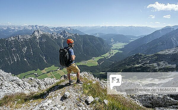 Mountaineer at the summit of the Obere Wettersteinspitze  view into the Leutasch valley  in the background summit of the Arnspitze  Wetterstein Mountains  Bavarian Alps  Bavaria  Germany  Europe