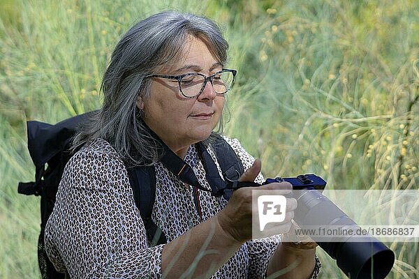 White-haired  bespectacled woman photographer reviewing her camera's pictures