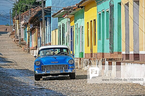 Blauer amerikanischer Chevrolet Oldtimer in einer gepflasterten Kolonialstraße mit pastellfarbenen Häusern in der Stadt Trinidad  Provinz Sancti Spíritus  Kuba  Mittelamerika